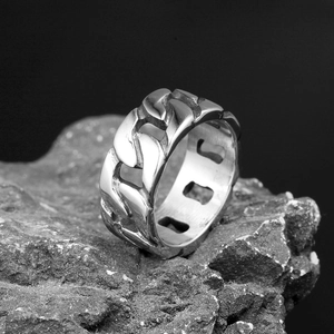 Detail of silver Cuban link chain ring for men on a black textured rock surface
