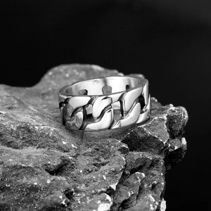 Polished stainless steel Cuban link ring for men on a natural dark rock background