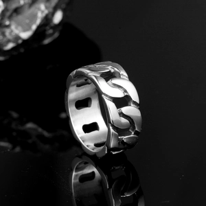 Macro shot of silver stainless steel Cuban link ring with polished finish on black mirror