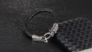 Detailed view of black braided leather bracelet with vintage silver dragon head clasp