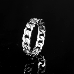 Polished silver stainless steel Cuban link ring with a clear reflection on a black background