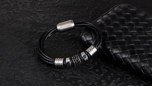 Detail of multi-strand black braided leather bracelet with silver beads and magnetic clasp