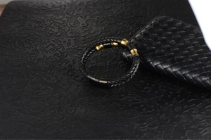 Close-up of woven leather bracelet with gold accents and black magnetic clasp