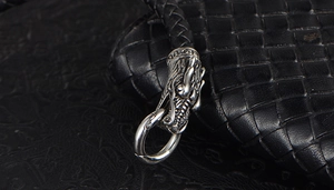 Macro shot of silver dragon head buckle on a black braided leather bracelet