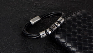 Detail of men's black multi-strand leather bracelet with silver metal beads and magnetic clasp