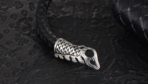 Macro detail of men's braided leather bracelet with vintage scale-textured steel clasp