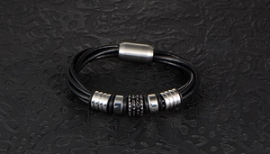 Detail of multi-layer braided leather bracelet with silver metal beads and magnetic clasp