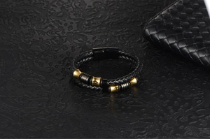 Detail of men's braided leather bracelet with golden beads and magnetic clasp on black background