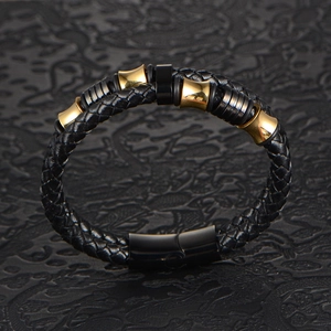 Men's braided black leather bracelet with gold metal accents and magnetic clasp