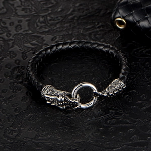 Braided leather bracelet with silver dragon head clasp on vintage textured background