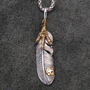 Detailed macro view of vintage feather pendant necklace with gold eagle claw and medallion