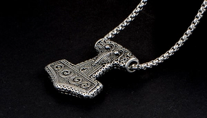 Macro shot of silver Thor's Hammer pendant with intricate Nordic engravings and chain