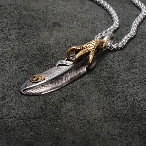 Detailed view of retro feather pendant with gold eagle claw and intricate metal textures