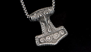 Detailed macro view of vintage silver Mjolnir pendant with Celtic relief and bead chain