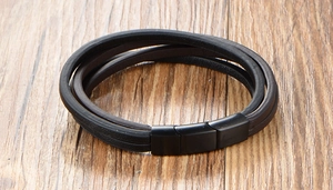 Vue macro d'un bracelet multicouche en cuir noir avec un fermoir magnétique noir mat