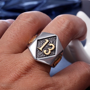 Detail of biker ring featuring golden number 13 on black honeycomb and skull carvings