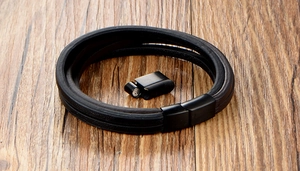 Détail d'un bracelet multicouche en cuir noir avec fermoir magnétique en métal sur bois