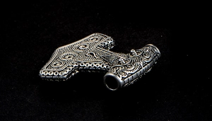 Macro detail of Thor's hammer pendant with vintage silver embossed vine patterns