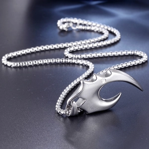 Macro shot of silver wolf tooth pendant in titanium steel with zircon on black surface
