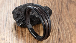 Gros plan d'un bracelet en cuir multicouche noir et marron avec fermoir magnétique sur pierre