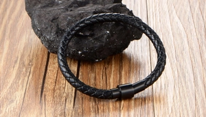 Close-up of black braided leather bracelet with matte magnetic clasp on a dark stone