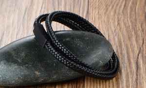 Detail of multi-layer black braided leather bracelet with matte black magnetic metal clasp