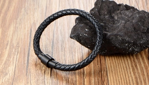 Macro view of black braided leather bracelet texture with matte magnetic clasp on rock