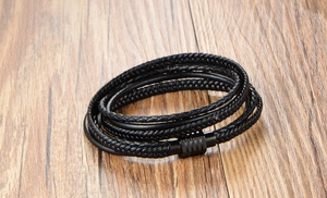 Détail d'un bracelet multicouche en cuir tressé noir avec fermoir magnétique sur bois