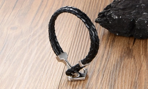 Macro detail of nautical anchor clasp on a black braided leather bracelet for men