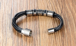 Close-up of men's braided black leather bracelet with engraved stainless steel charms
