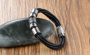 Detail of multi-layer black leather bracelet with silver metal rings on pebbles