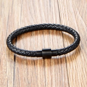 Braided black leather bracelet with matte black metal clasp on a wooden surface