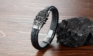 Macro detail of men's black braided leather bracelet with gothic alloy crest and magnetic clasp
