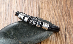Close-up of men's multi-layer black braided leather bracelet with vintage scrollwork beads