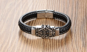 Detail of black braided leather bracelet featuring a silver stainless steel cross clasp