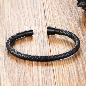 Braided black leather bracelet for men with magnetic metal clasp on wooden background