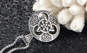 Macro view of vintage Celtic Triquetra knot pendant with distressed finish on pearl chain