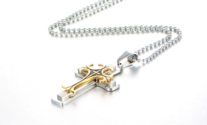 Macro detail of triple-layer stainless steel cross pendant with golden cutout overlay