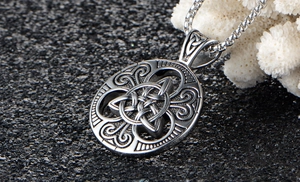 Macro detail of Celtic knot pendant with box chain on a dark stone background