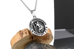 Macro view of Saint Christopher medal pendant on stainless steel chain over rustic wood