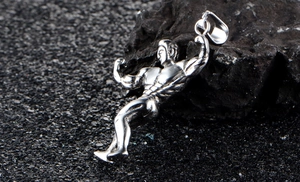 Makrodetail eines silbernen Bodybuilding-Anhängers aus Edelstahl auf dunklem Stein