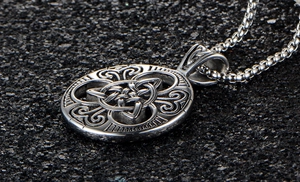 Macro shot of silver Celtic knot pendant with vintage textures and square pearl chain