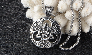 Detailed macro view of silver Celtic Triquetra pendant on a black textured surface