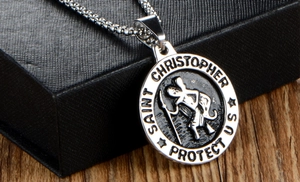 Close-up of Saint Christopher religious medallion on a silver box chain over a black case