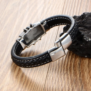 Men's punk braided leather bracelet with silver metal buckle on a rustic wood background