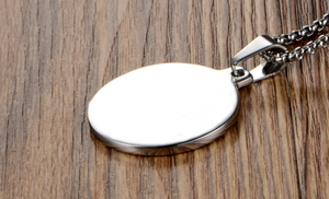 Close-up of polished oval titanium steel pendant on a chain over a wooden background