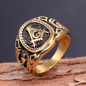 Vintage gold Freemasonry ring with G symbol on a rustic wood background