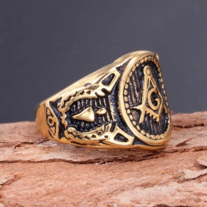 Vintage golden Freemasonry compass ring with G logo on dark textured bark background