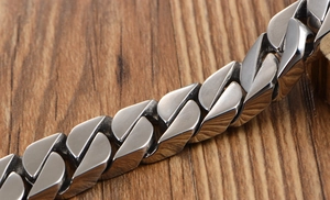 Macro shot of polished silver Cuban link chain bracelet on a rustic wood background