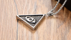Gros plan du pendentif triangle vintage en acier inoxydable All-Seeing Eye sur bois